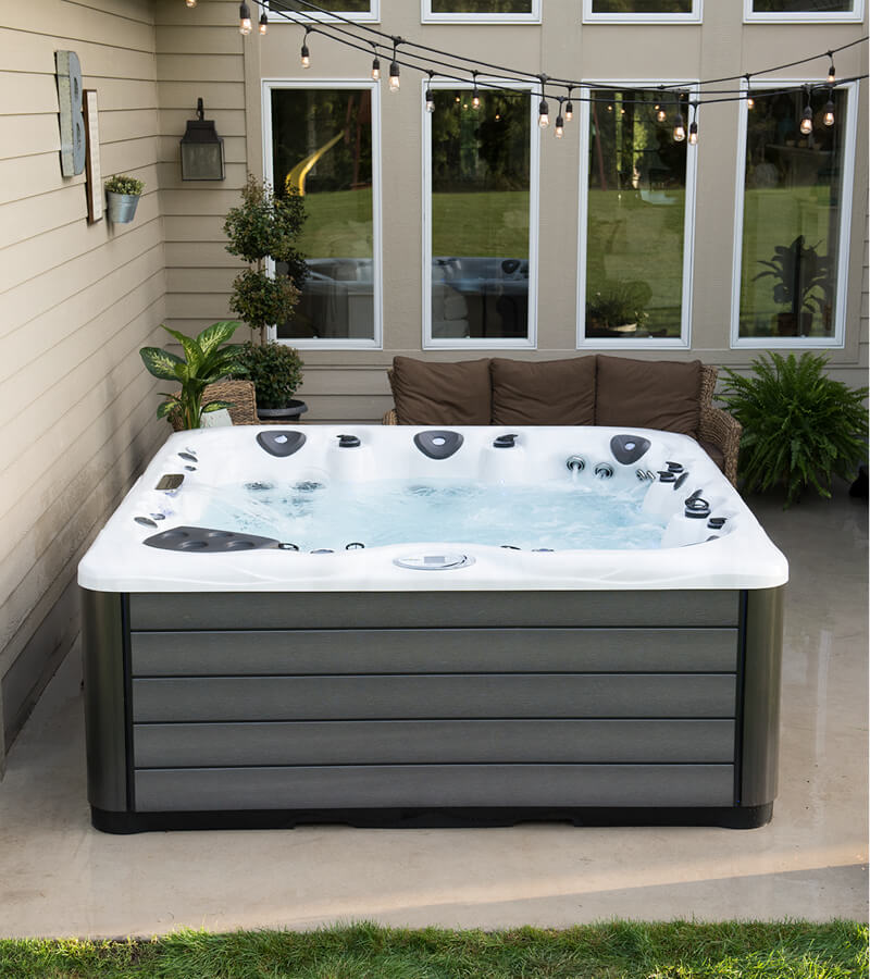 Small Backyard, Big Design. Cozy patio feature shot tub, outdoor couch, and large planters.